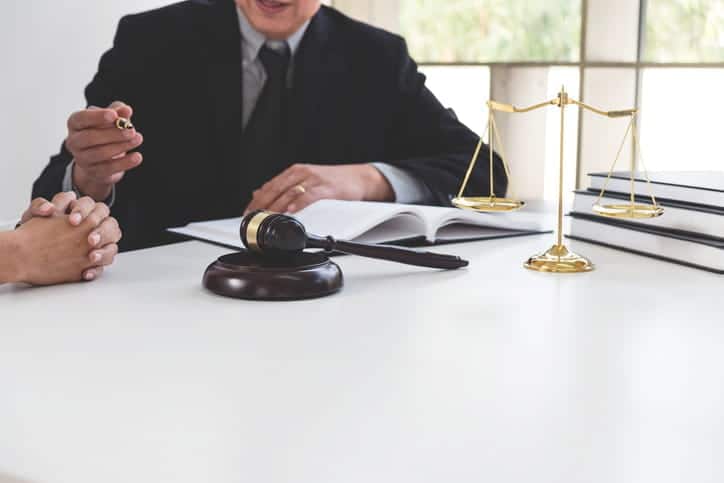 What Is Legally Considered A &Quot;Vicious Dog&Quot;? 2 A dog bite attorney speaks with his client at his desk. In front of him is paperwork, a gavel, a stack of books and the scales of justice.