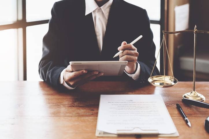 A medical malpractice attorney working on paperwork at his desk. Next to him is the scales of justice. 