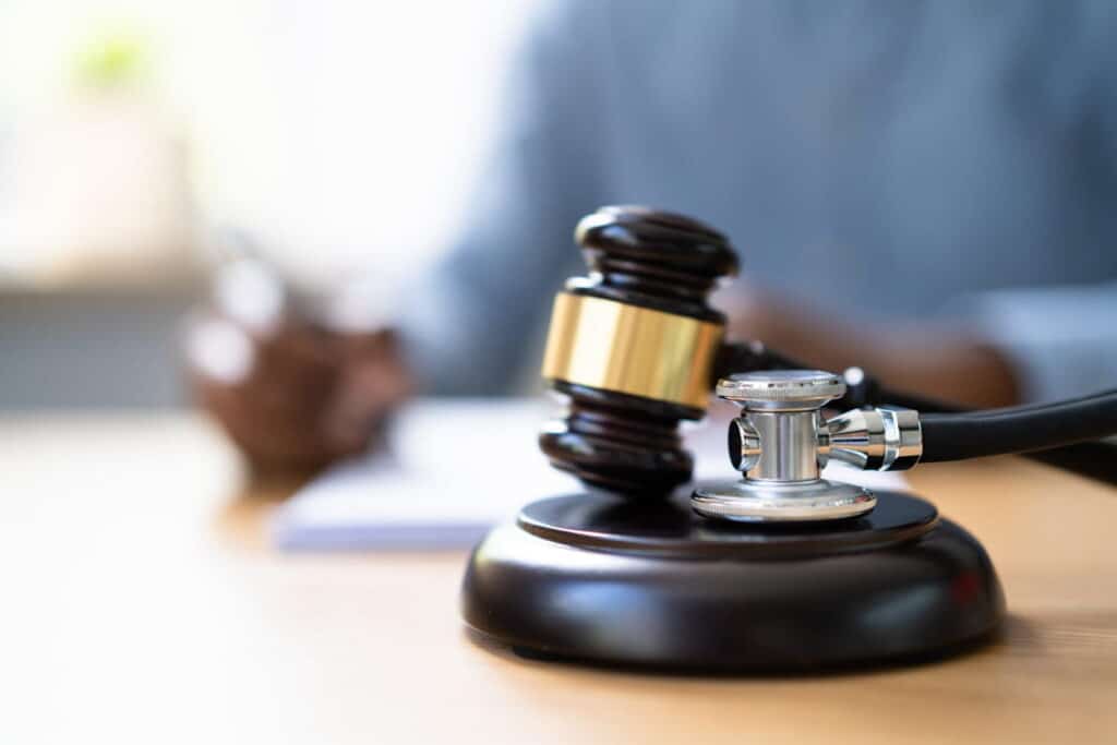 A stethoscope resting on a gavel with a personal injury attorney blurred out in the background. 