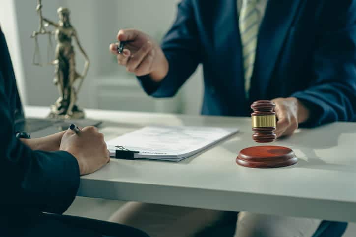 A premises liability attorney reviewing a case with their client. In front of them is paperwork and a gavel, next to them is a lady justice statue.