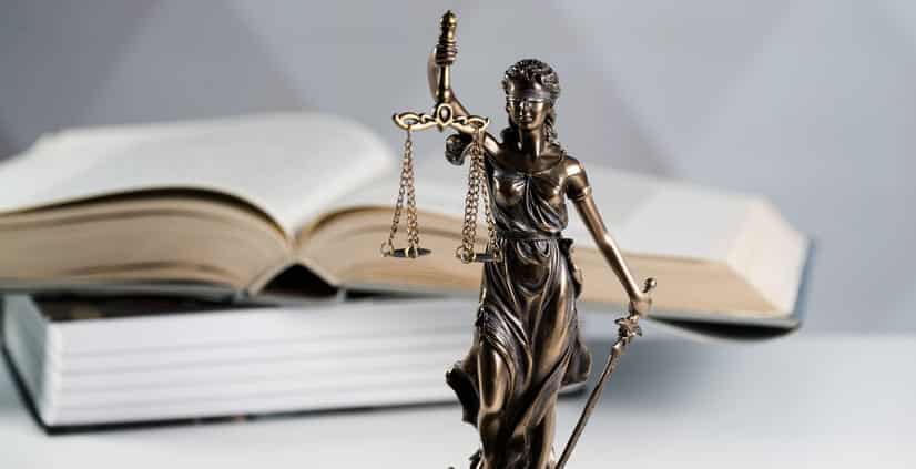 A Lady Justice statue in front of a stack of books. 