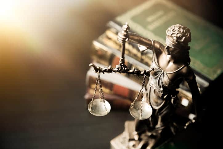 A Lady Justice statue in front of a stack of books. 