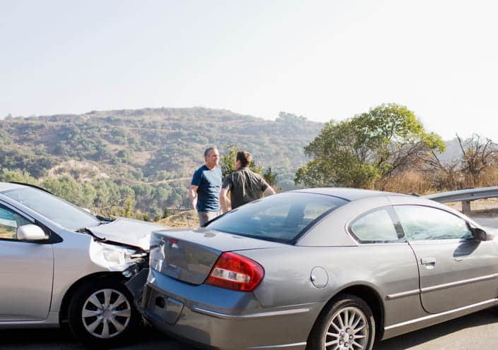 Two men arguing outside of their damaged vehicles after being in a rear-end collision. 