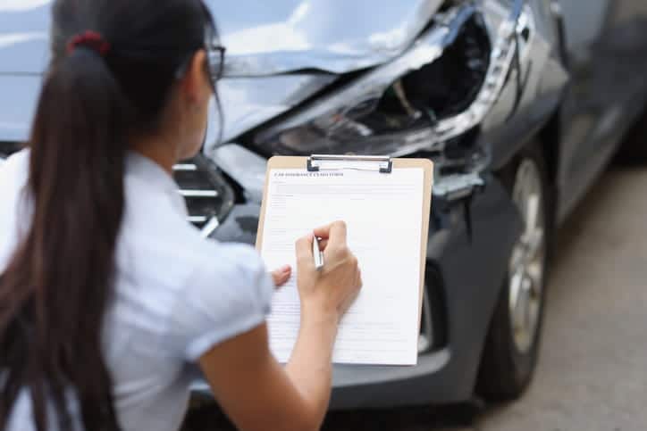 A claims adjuster making a report of the damage inflicted on a vehicle after a car accident. 