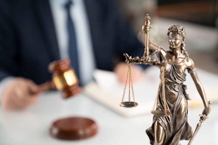 Paradise Motorcycle Injury Attorney 1 A lady justice statue with a motorcycle accident attorney using a gavel blurred out in the background.