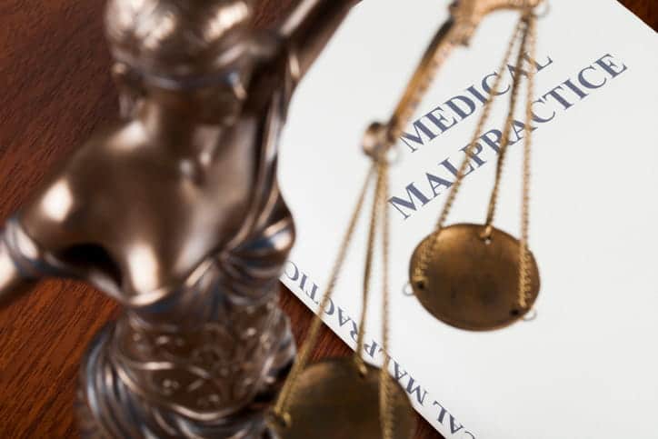 A Lady Justice statue on top of a medical malpractice law book. 