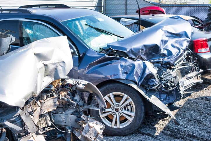 Two severely damaged vehicles in a junk yard after being deemed totaled. 