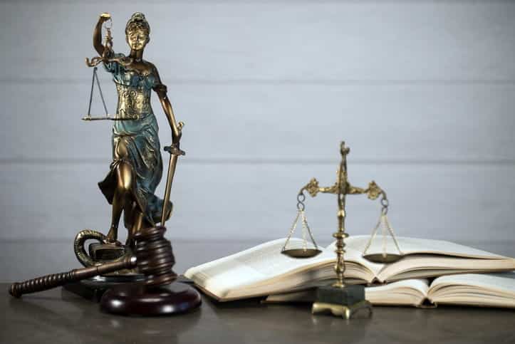 Paradise Motorcycle Injury Attorney 1 A lady justice statue, a gavel, and open book, and the scales of justice on a motorcycle accident injury attorney's desk.