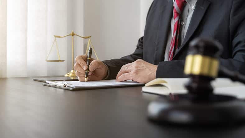 A car accident attorney working on paperwork at his desk. Next to him is the scales of justice and a gavel. 