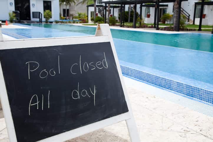 A hotel pool with a sign that reads: "Pool closed all day."