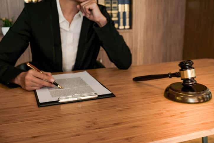 A premises liability lawyer working on paperwork at her desk. Next to her is a gavel. 