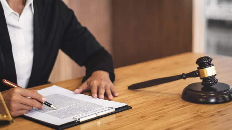 A workers' comp attorney working on paperwork at their desk. Next to them is a gavel. 