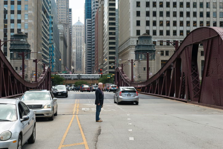 A jaywalker crossing the road in the middle of traffic.