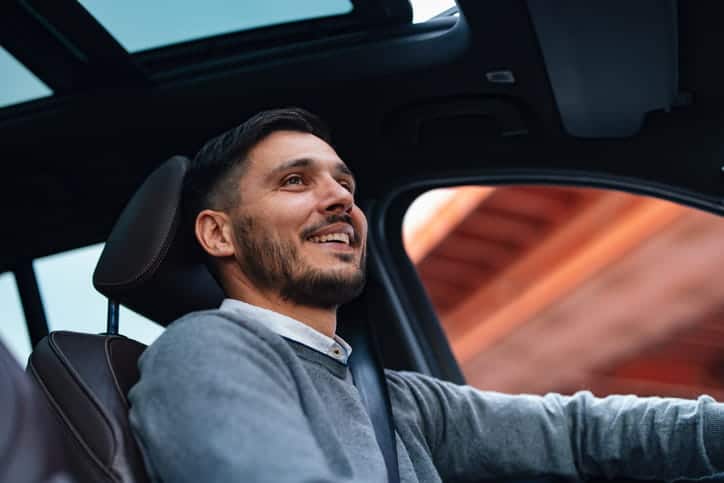 A man smiling as he drives a vehicle.