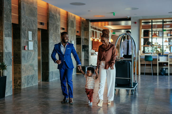 Child Safety And Premises Liability: Tips For Property Owners And Parents 1 Two parents with their young child smiling as they check into a hotel.