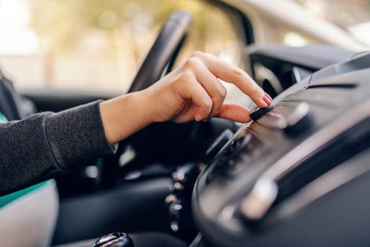 Focus is on a driver turning the volume up on their vehicle while driving.
