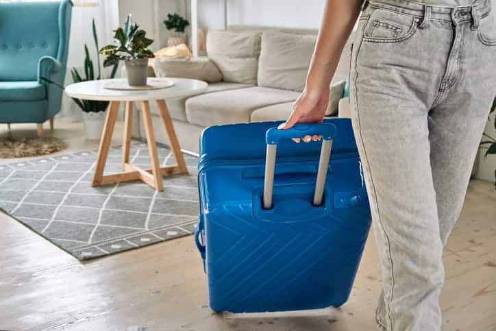 A woman rolling a suitcase as she visits an airbnb.
