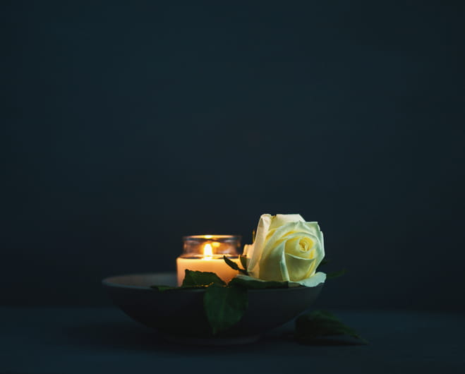 A yellow rose next to a lit candle in a memorial for a wrongful death.