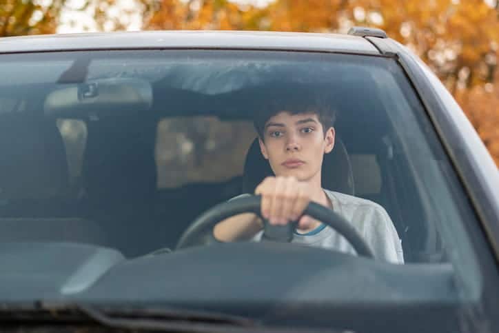 A teen driver behind the wheel of a vehicle.