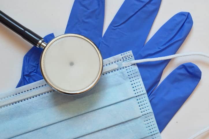 Proving Negligence In A Medical Malpractice Case 1 A medical glove, a mask, and a stethoscope all layered over one another.