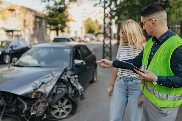 An auto accident attorney assesses the damage of a vehicle with a client after a car accident.