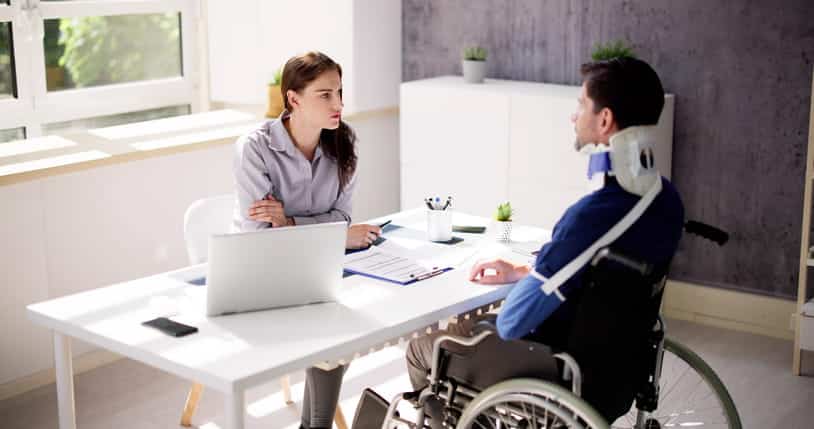 Black Hills 12 A man in a neck brace, arm sling, and sitting in a wheelchair speaks with his personal injury attorney.