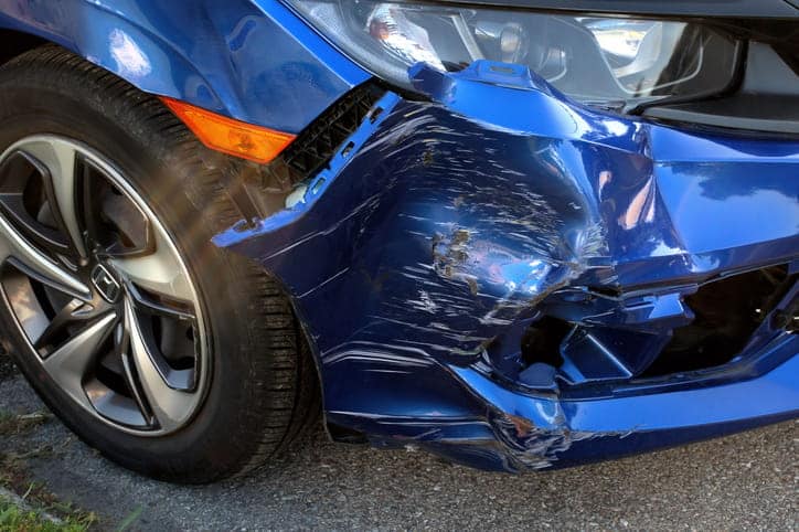 A badly damaged front end of a blue vehicle after a car accident.