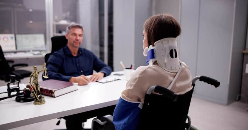 Spring Valley 12 A woman in a neck brace and arm sling sits in a wheelchair as she speaks with her personal injury attorney.