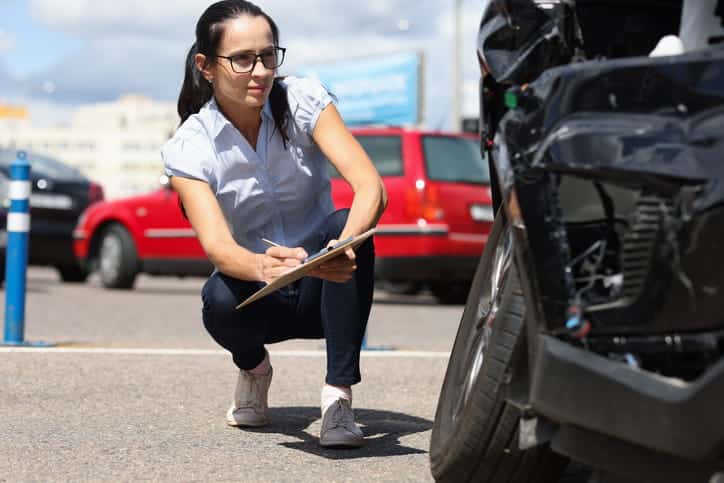 An insurance adjuster looking at the damage of a vehicle after a car accident.