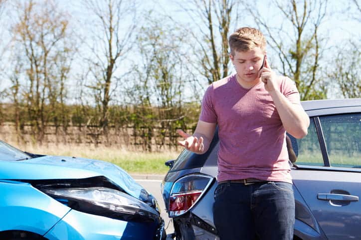 A young man on the phone with his insurance company after being in a car accident.