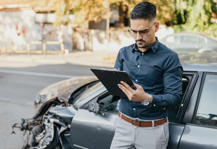 An insurance adjuster inspecting the damage of a vehicle after a car accident.