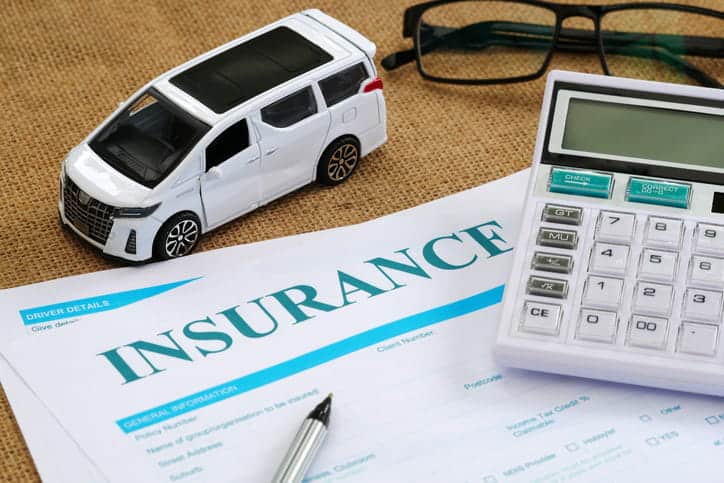 A form that reads "insurance" with a calculator, pen, glasses, and a toy car surrounding it.