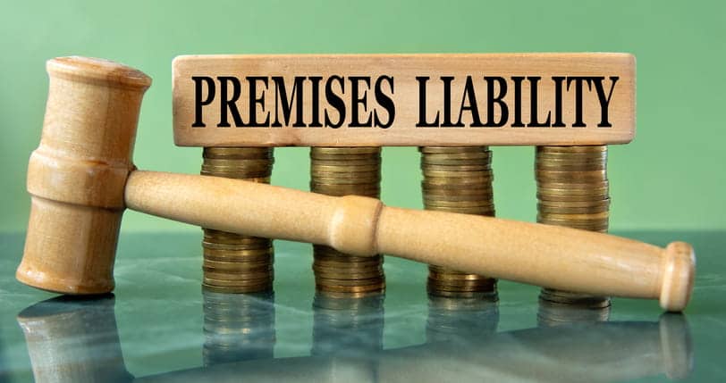 A block that reads "premises liability" on a stack of coins with a wooden gavel in front of it.