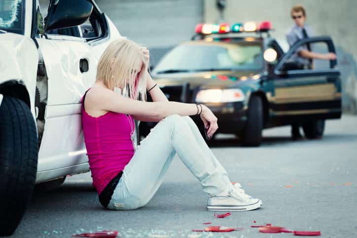 How Emotional Distress Claims Work After A Car Accident 1 A woman in emotional distress sitting outside of her vehicle after a car accident.