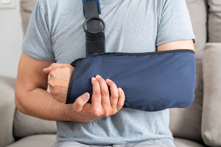 A man in an arm sling after a delayed injury from a car accident.