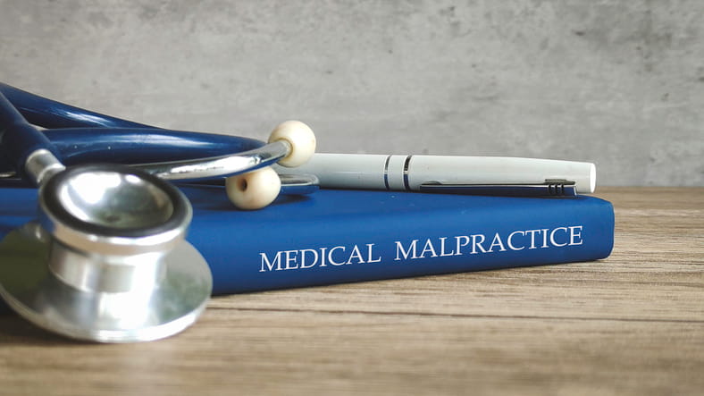A book that reads "medical malpractice" along with a stethoscope.