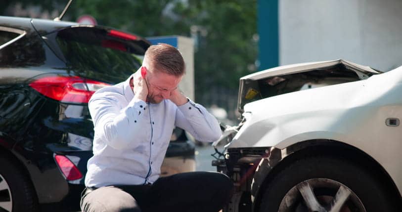 A man holds his neck in pain after a car accident.