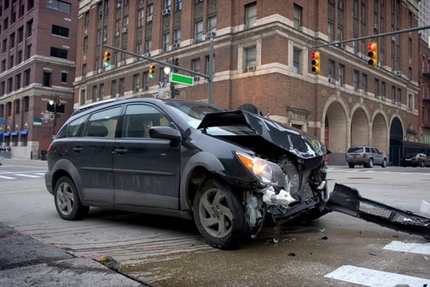 Severe damage to the front end of a vehicle after a t-bone accident at an intersection.