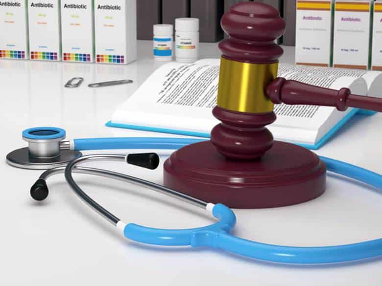 A gavel next to a stethoscope and a medical journal.