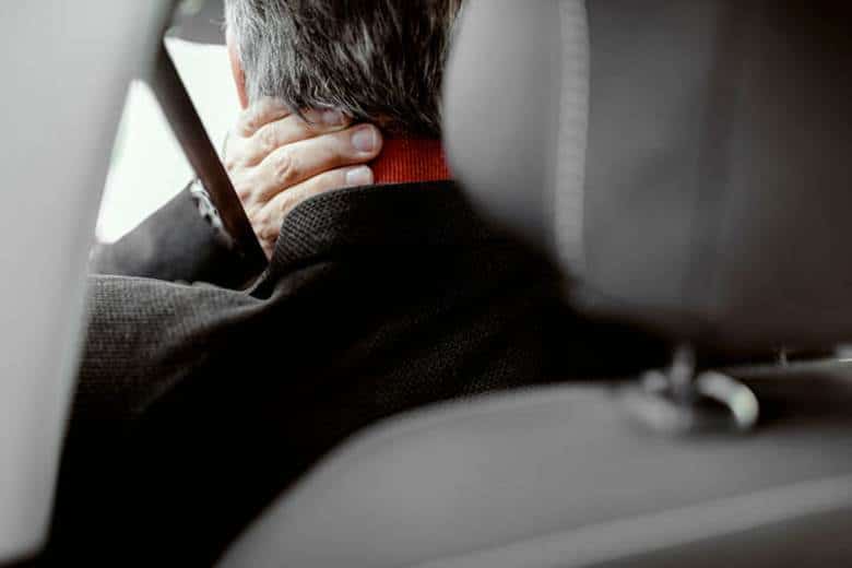 Average Whiplash Settlement In Nevada 1 A man holding his neck while in the car due to whiplash.