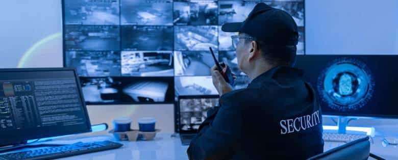 A security guard on his radio as he watches security cameras.