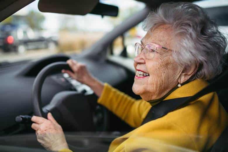 Nevada Driving Laws For Seniors And Older Drivers 23 An elderly woman smiling while behind the wheel of a vehicle.